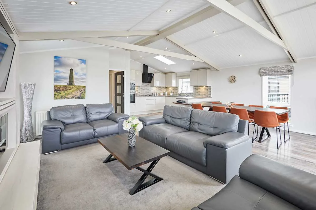 An open-plan living and dining area with gray seating and a kitchen.