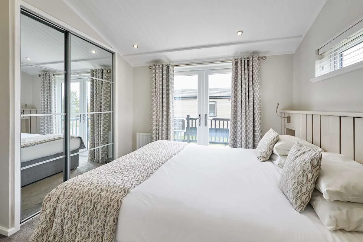 A bright bedroom with a large bed and glass doors opening onto a balcony.