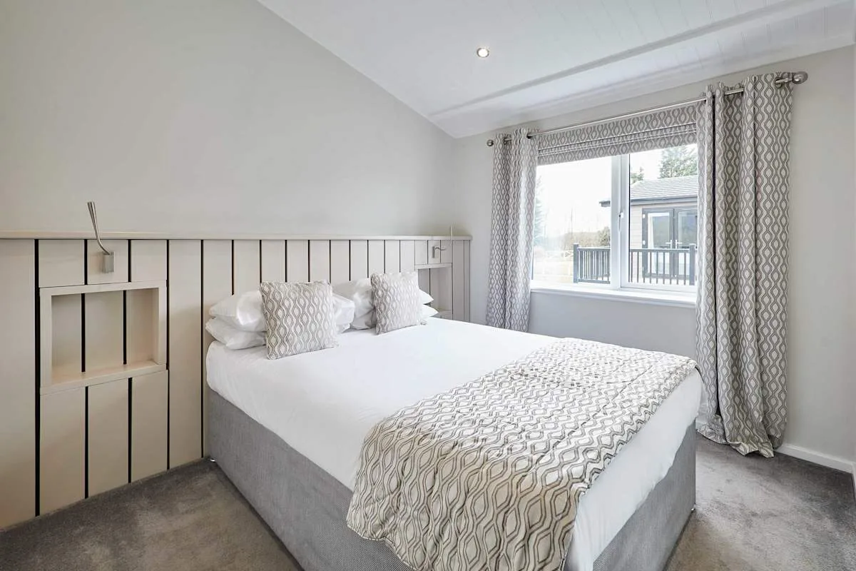 A bright bedroom with a bed and a window framed by curtains.