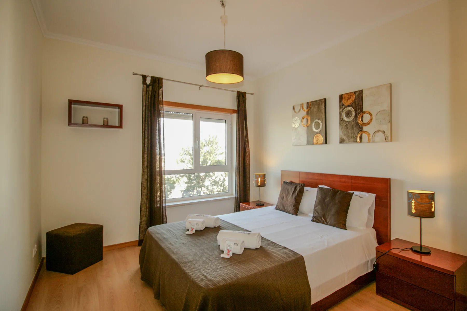 Un dormitorio con una cama junto a una ventana y mesillas de noche.