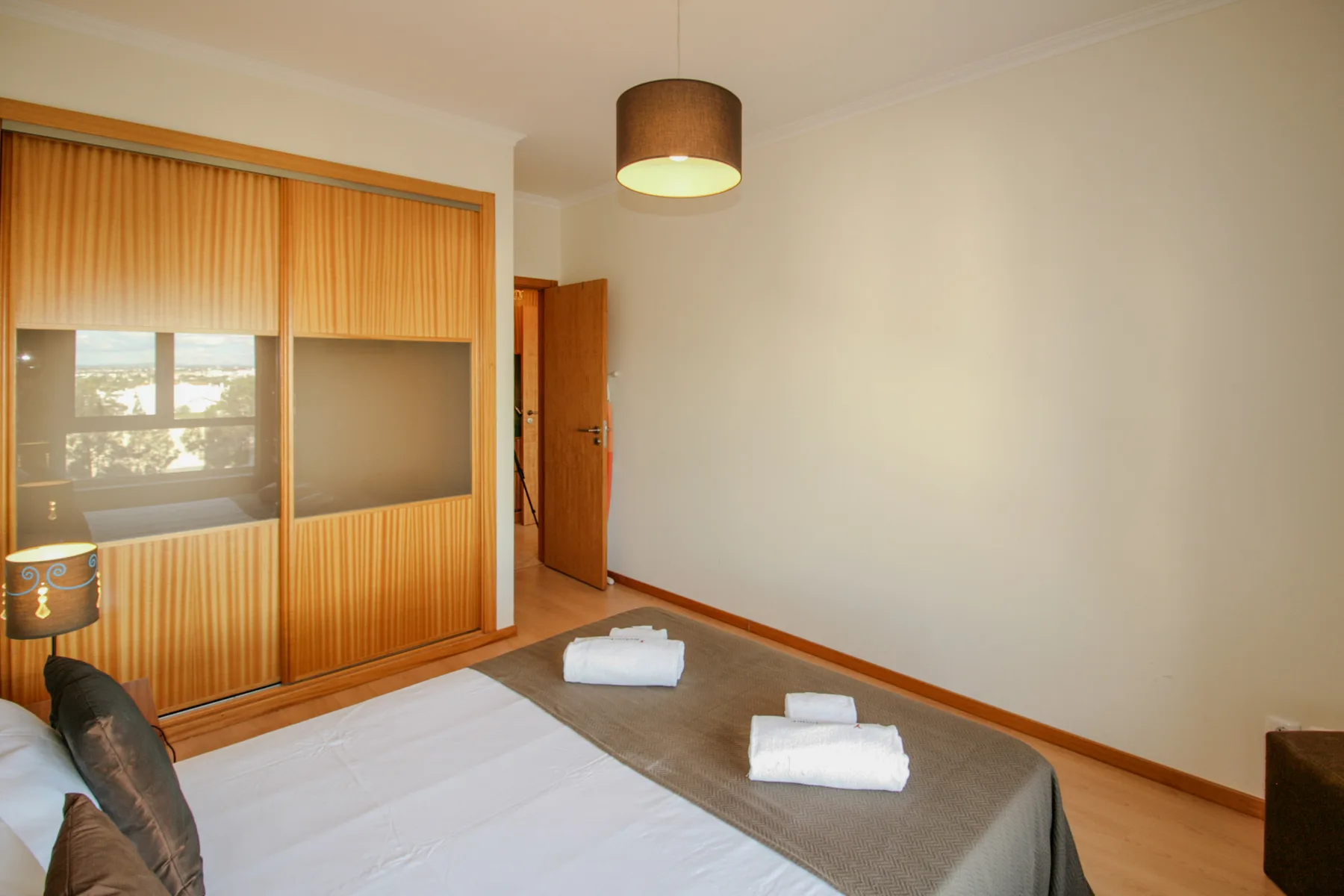 Dormitorio con cama, armario de madera y una puerta abierta.