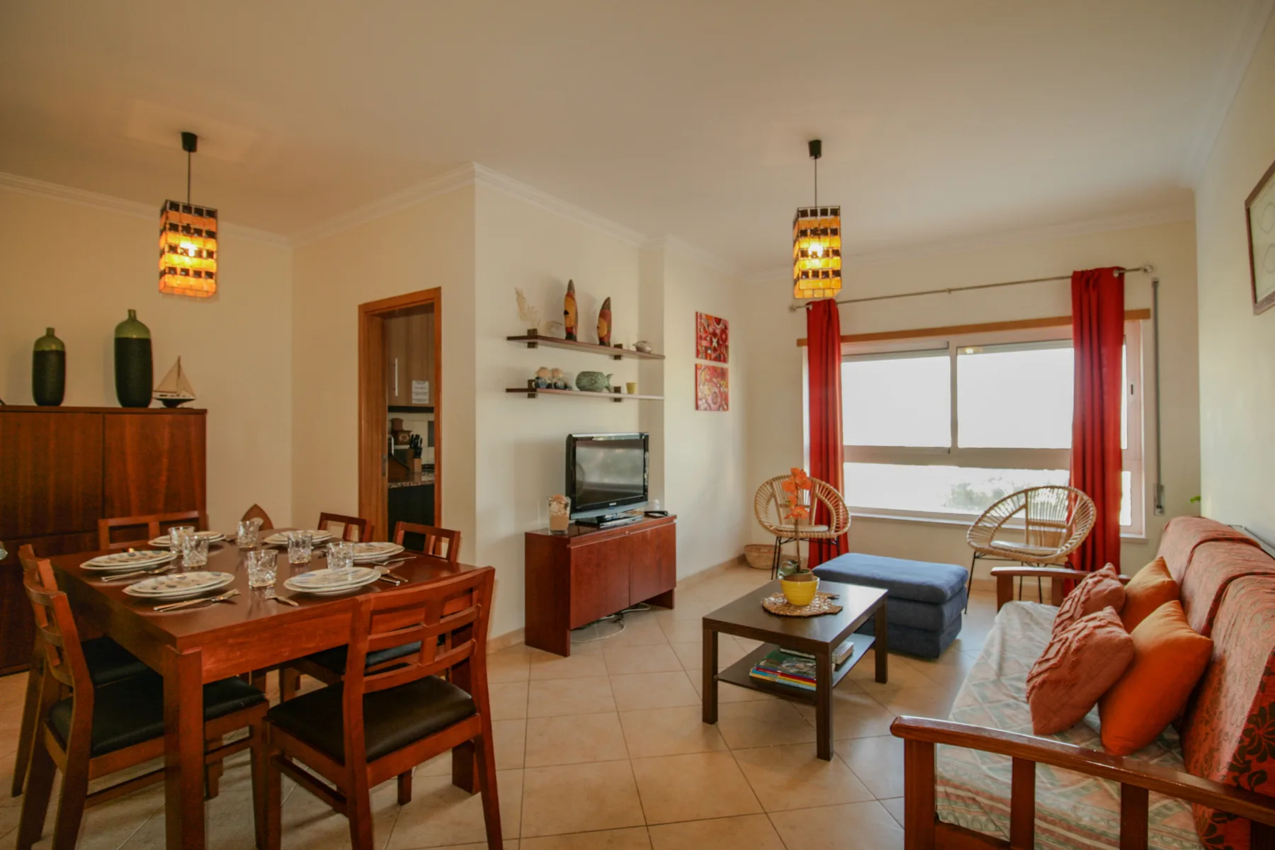 Una sala de estar y comedor con televisor, mesa de comedor y asientos junto a la ventana.