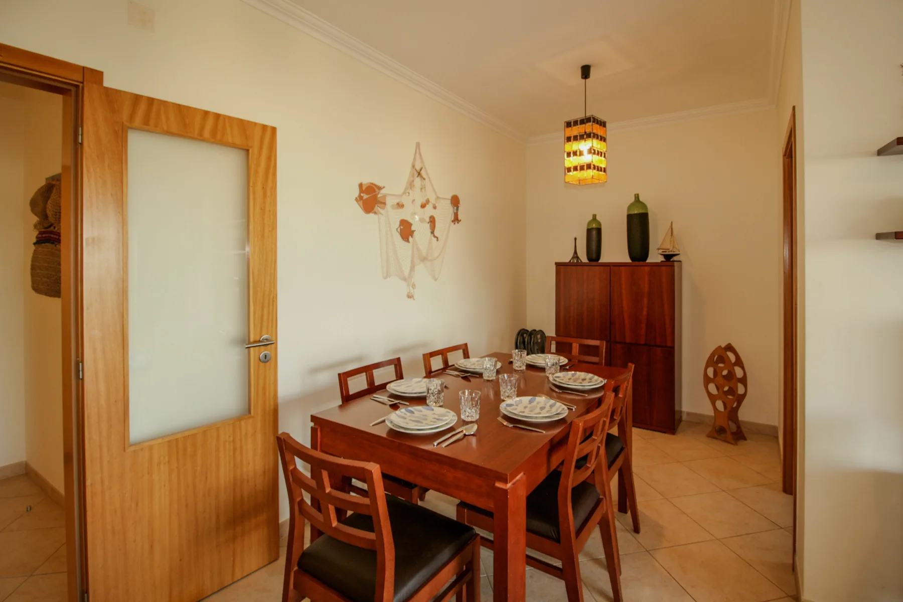 Un comedor con una mesa de madera y sillas bajo una lámpara colgante.