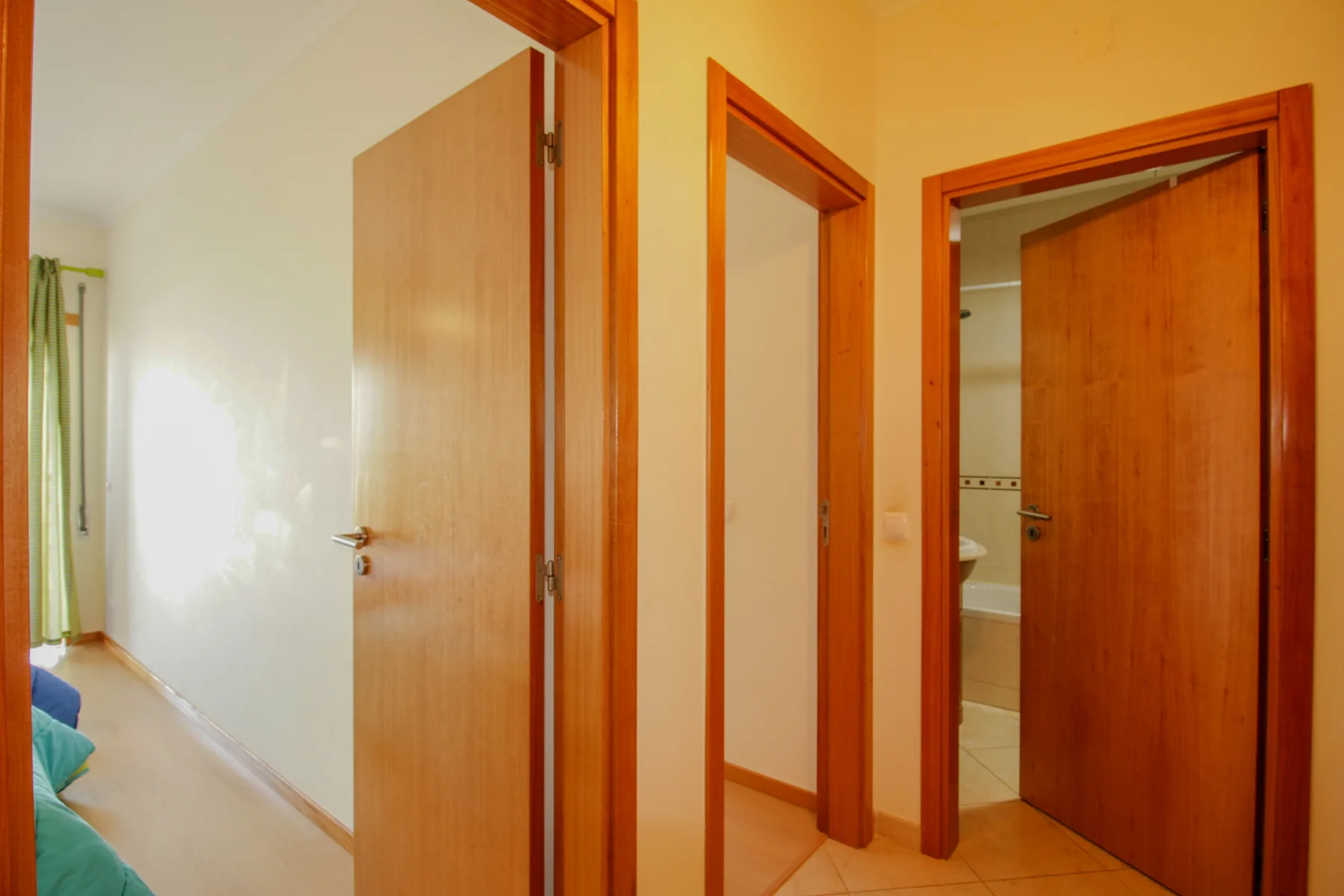 Un pasillo con puertas de madera y una vista parcial del baño.