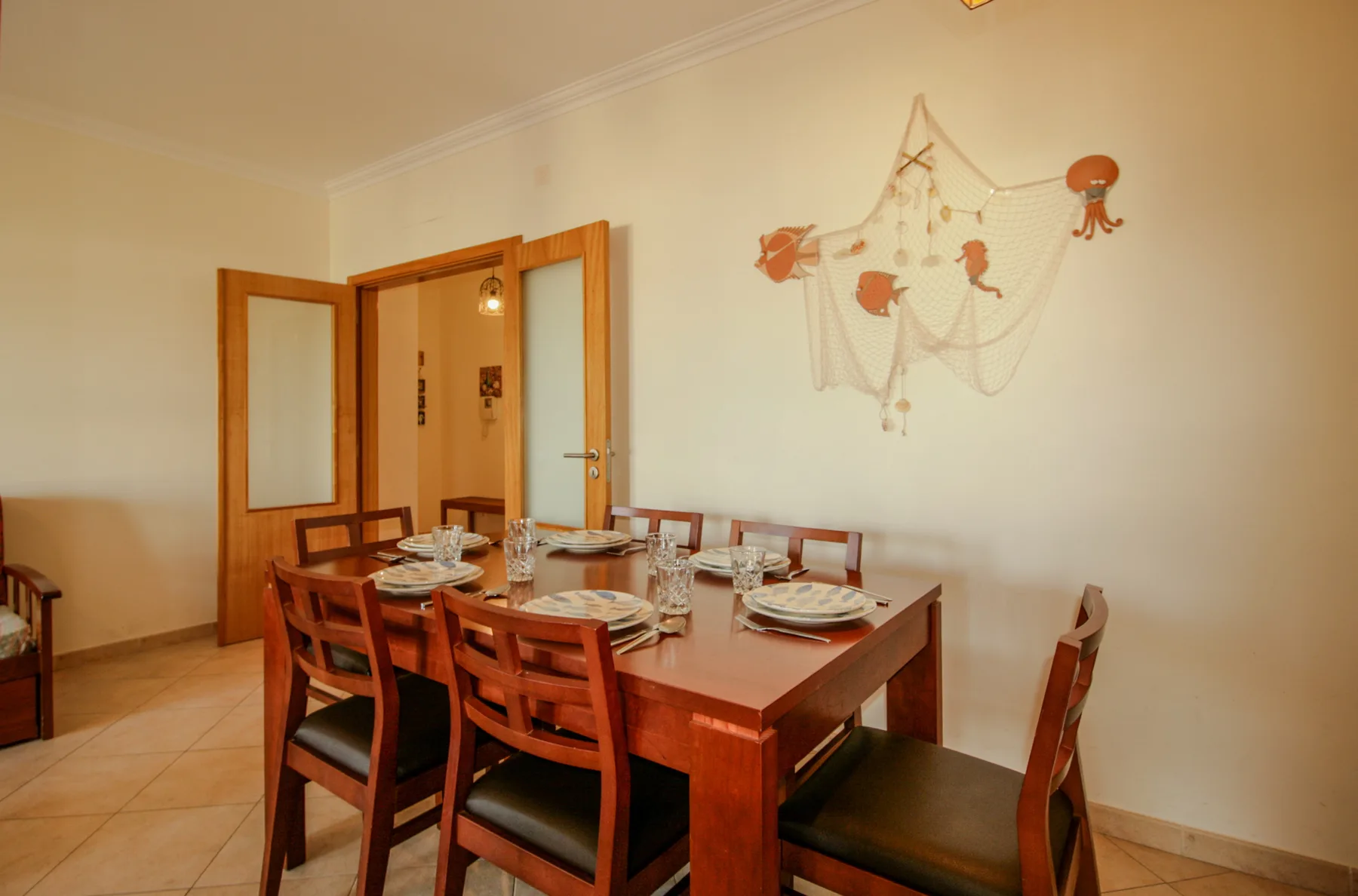 Un comedor con una mesa de madera y sillas bajo un adorno de pared.
