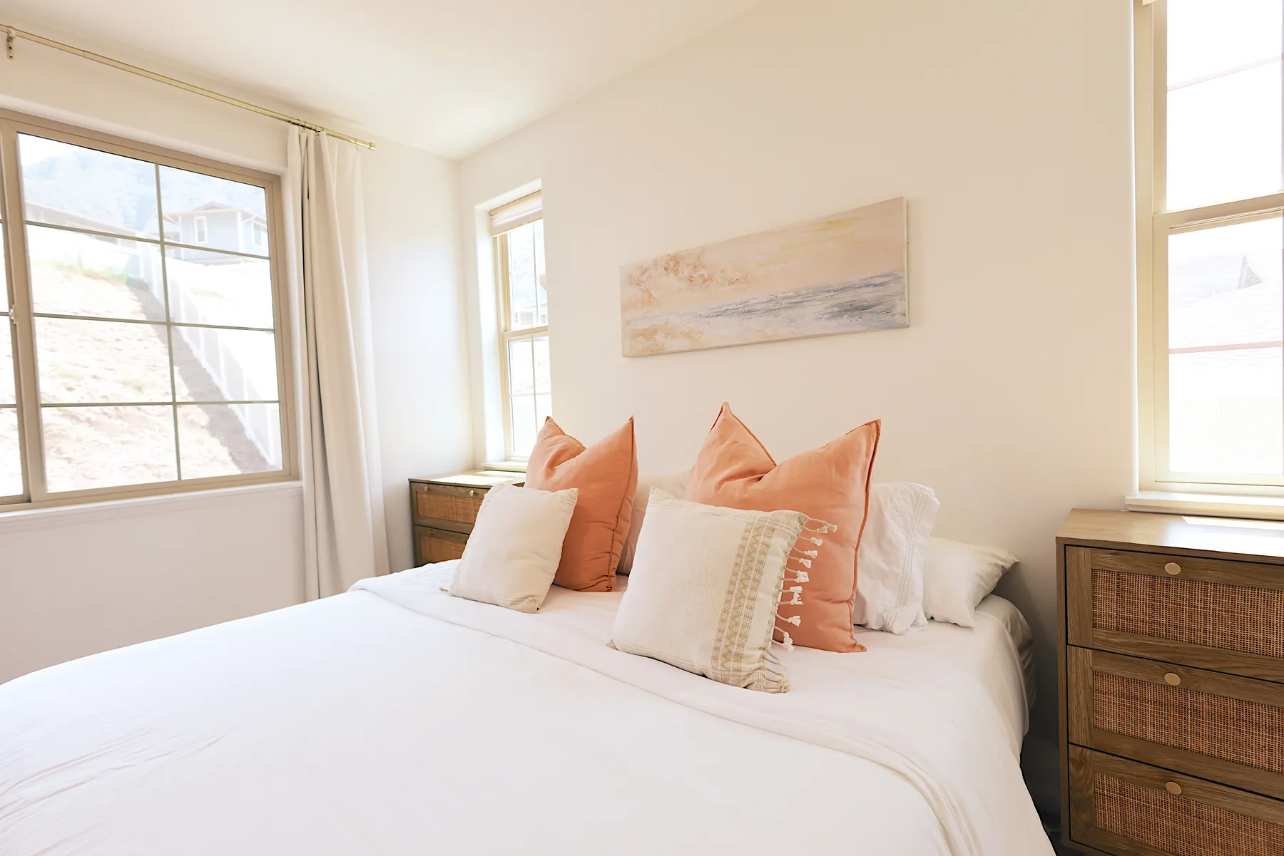 Un dormitorio luminoso con una cama bien tendida y paredes claras.