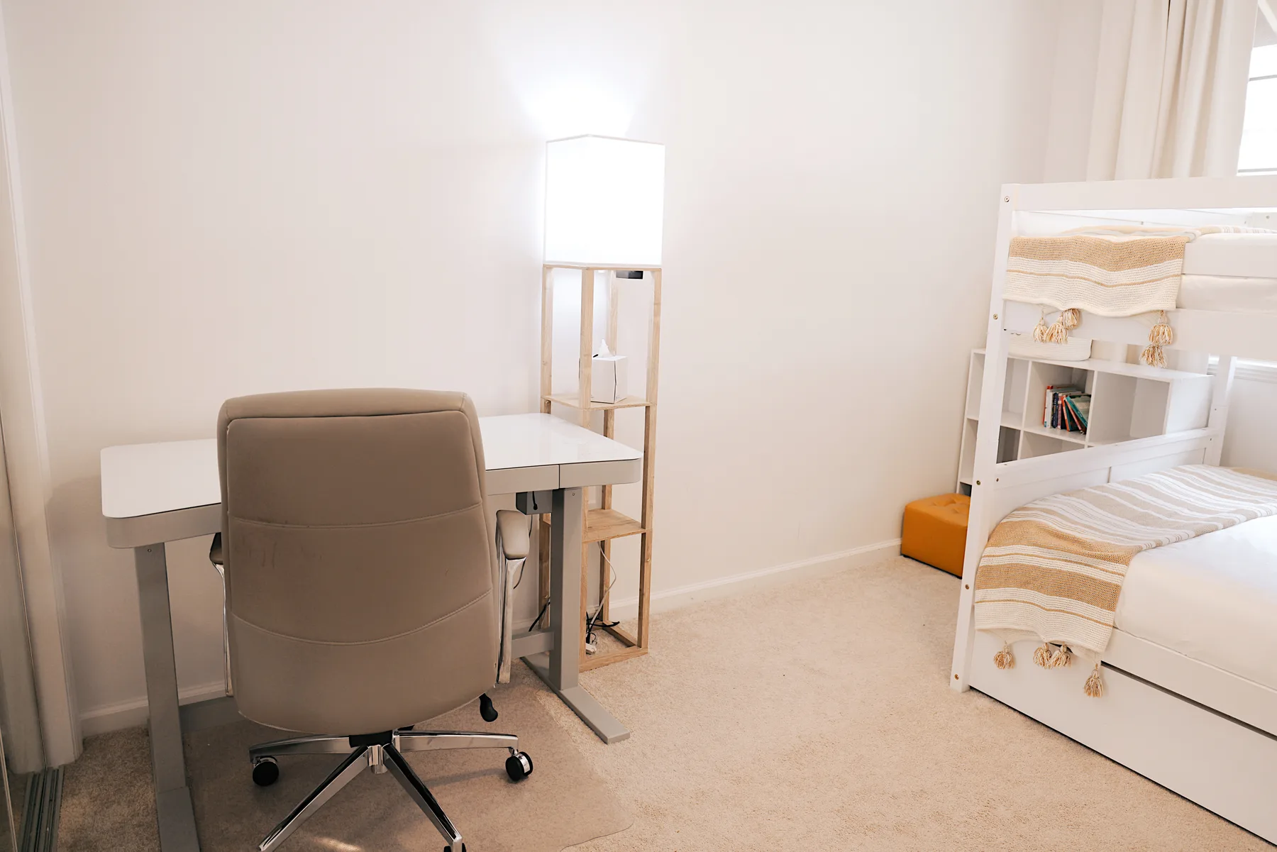 Un dormitorio con un escritorio y una silla junto a una litera.