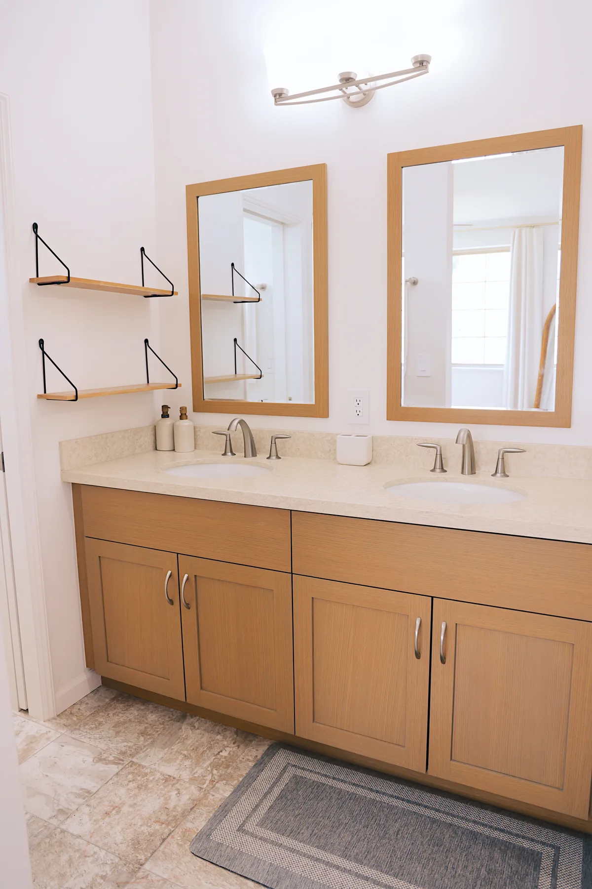 Un tocador de baño con una encimera larga, dos lavabos y espejos enmarcados.