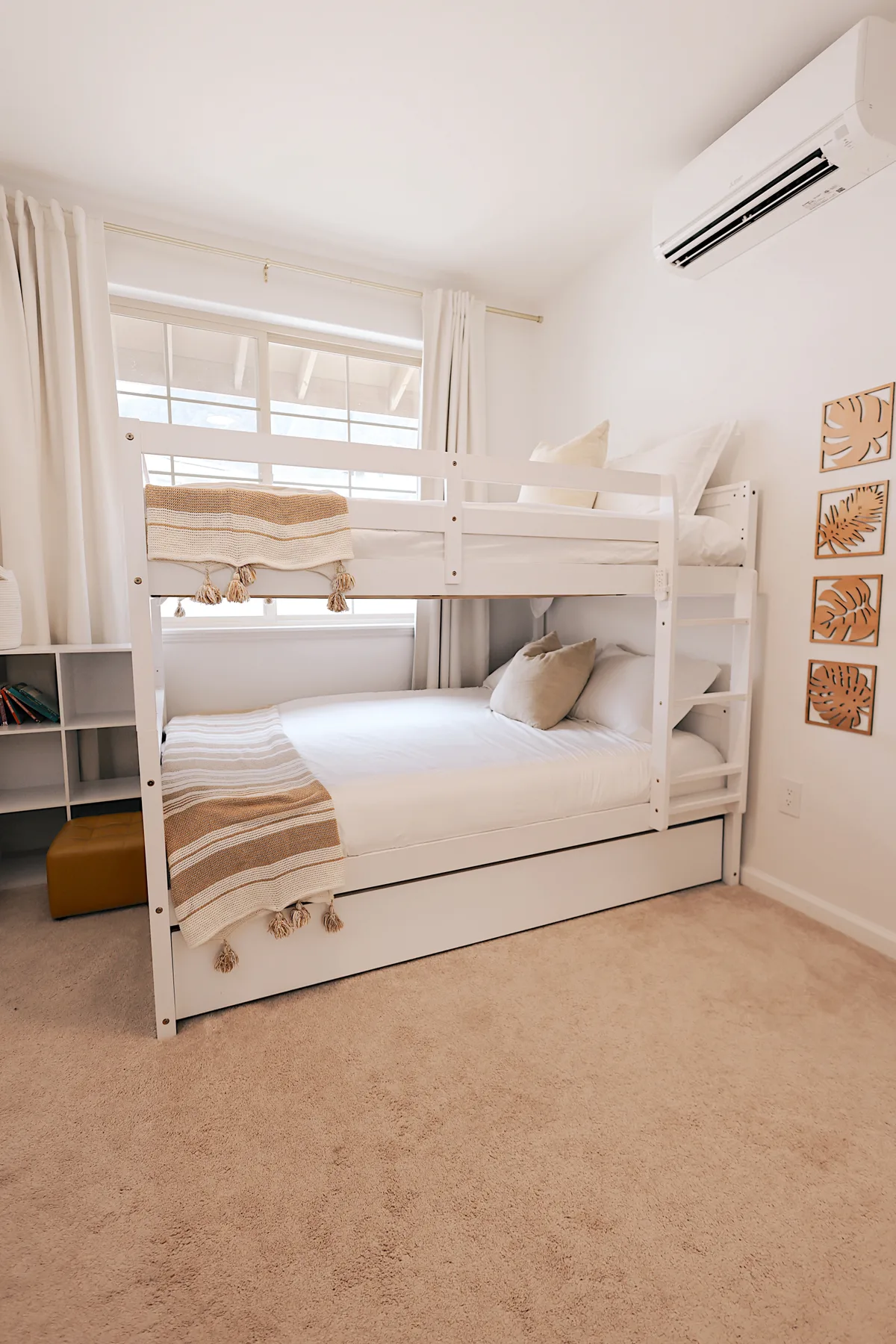 Dormitorio luminoso con una litera blanca, ropa de cama a rayas y una ventana.