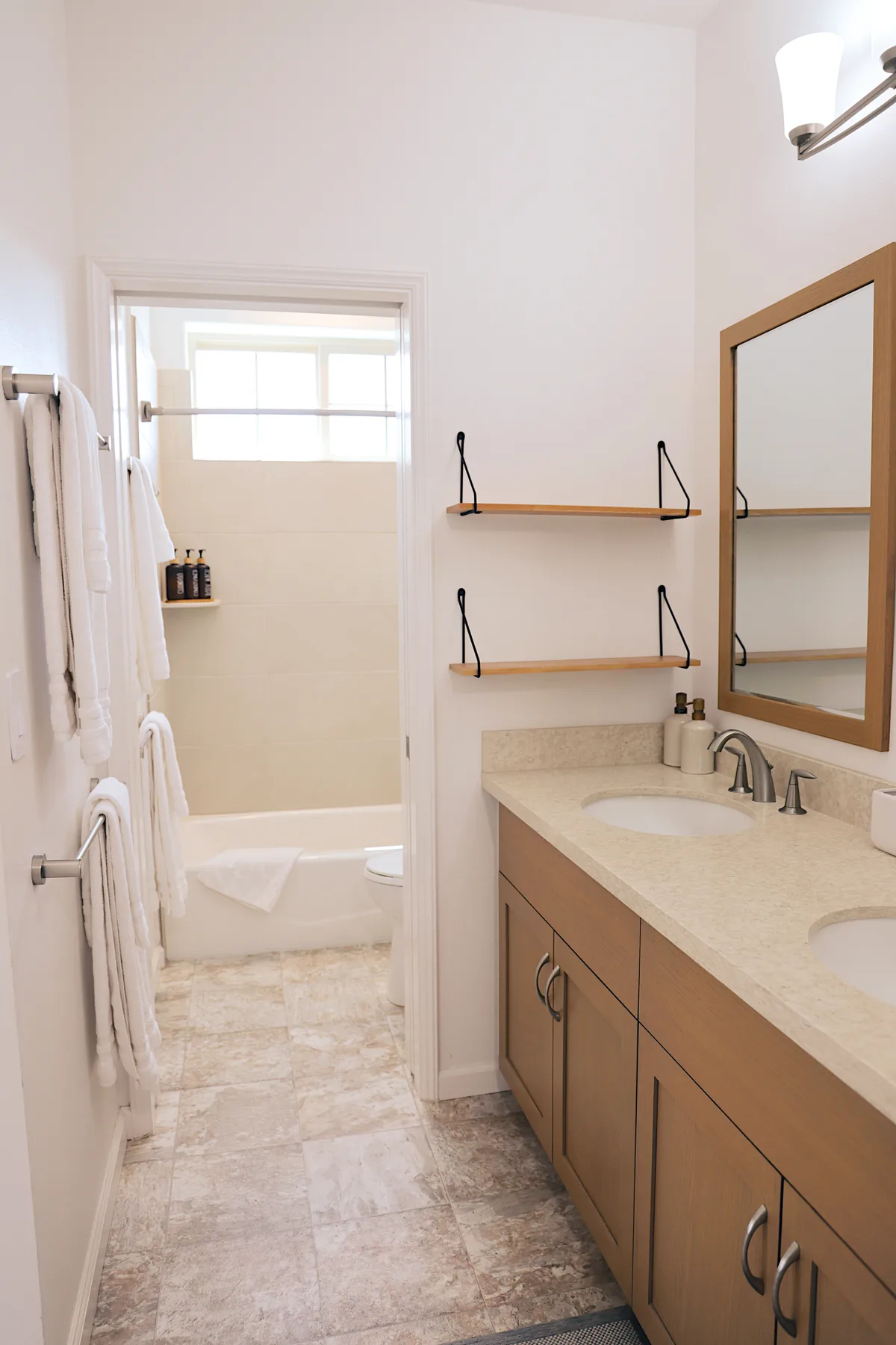Un baño con un tocador largo y una bañera visible a través de la puerta.