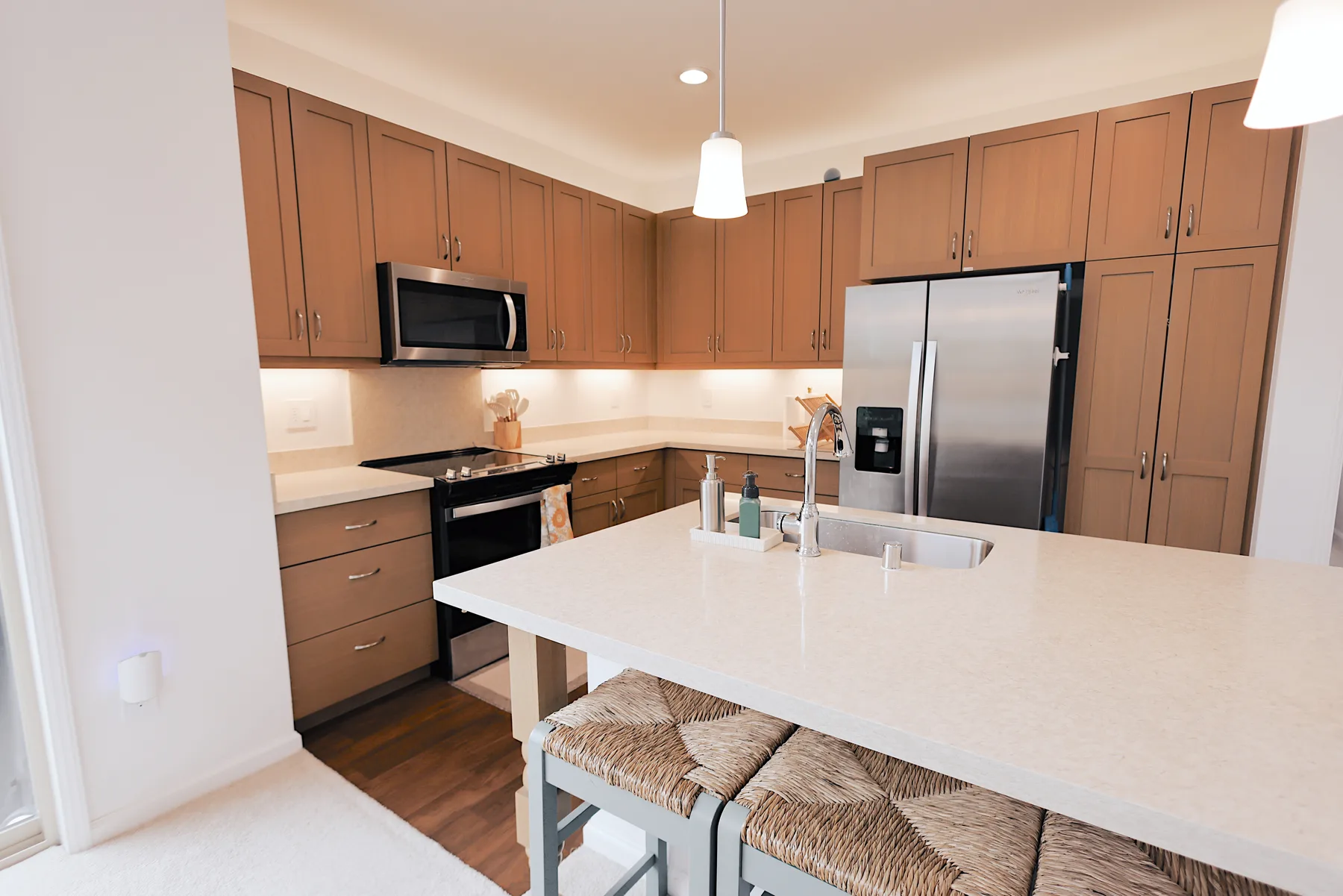 A bright kitchen with wooden cabinets, stainless steel appliances, and a large island.