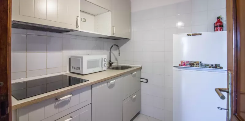 A compact kitchen with a microwave, sink, and white refrigerator.