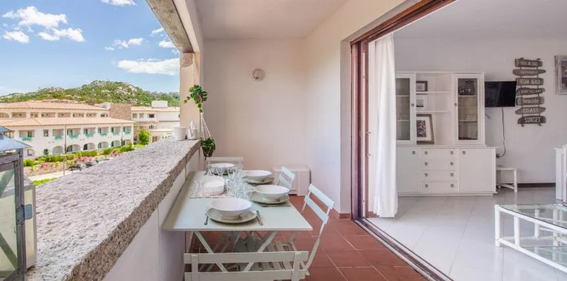 A terrace dining area overlooks nearby buildings, with a table set beside the open doorway.