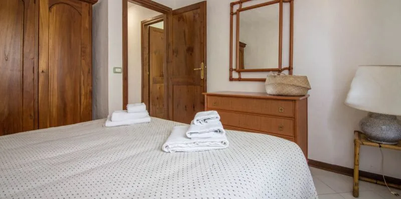 A bedroom with a neatly made bed and folded towels.