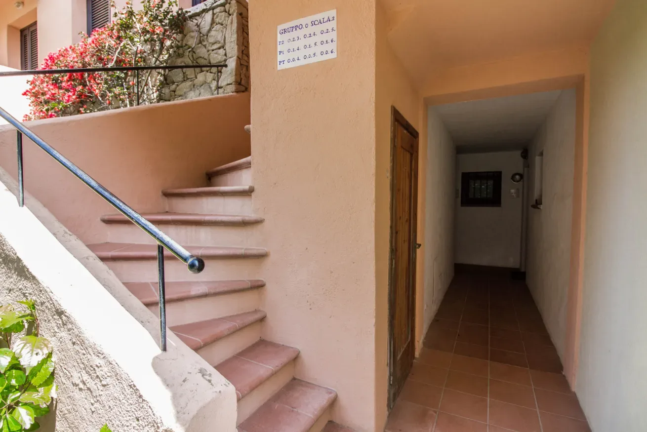 An indoor stairway beside a tiled hallway.