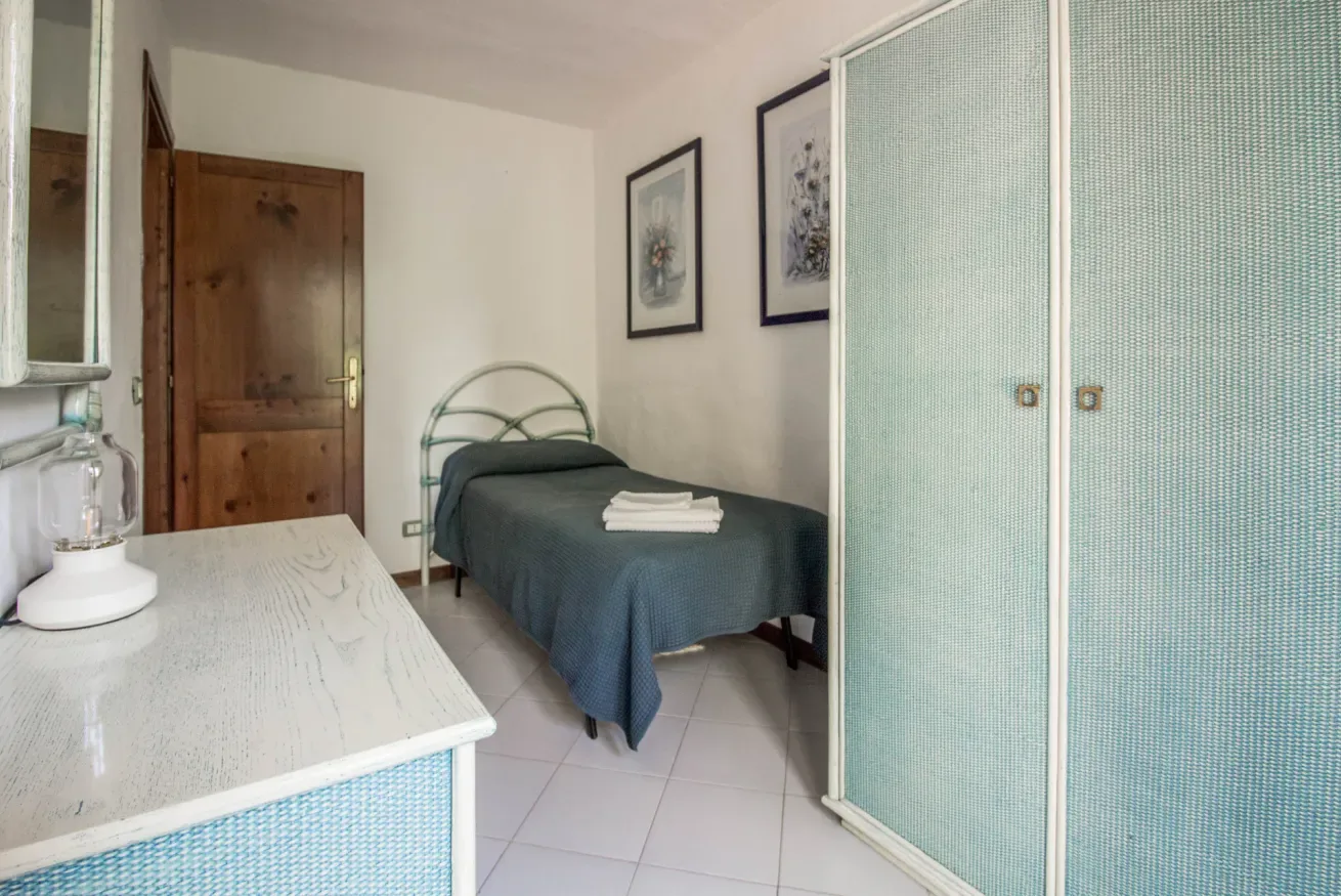 A bedroom with a single bed, bedside table, and sliding wardrobe.