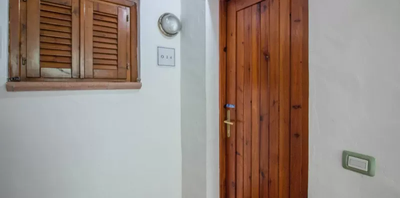 A wooden door and shuttered window on a white interior wall.