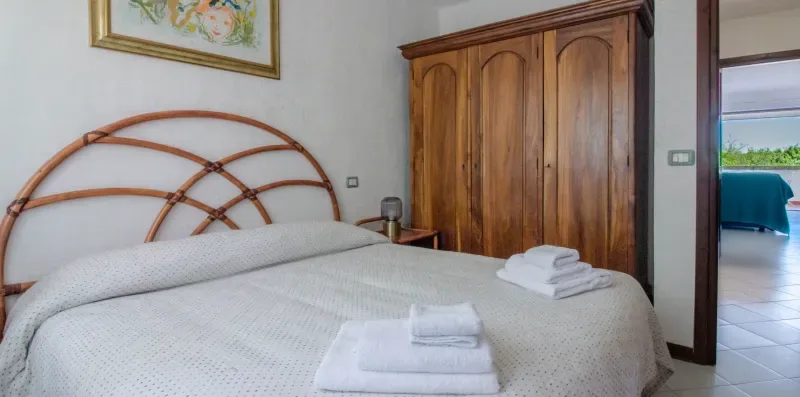 A bedroom with a neatly made bed and folded towels.