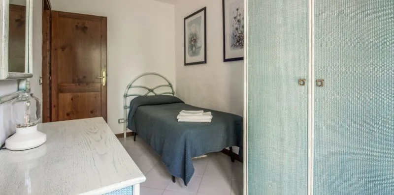 Un dormitorio con una cama individual, toallas dobladas y una puerta de madera.