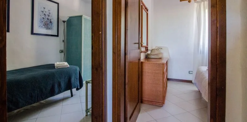 A bedroom with a bed, a wardrobe, and a small dresser beside the window.