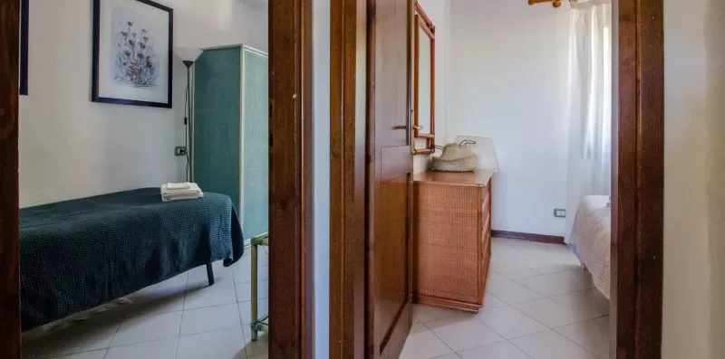 A bedroom with a bed and a wooden cabinet beside a bright window.