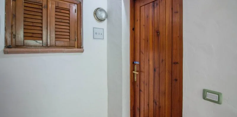 A white interior wall with a wooden door and shuttered window.