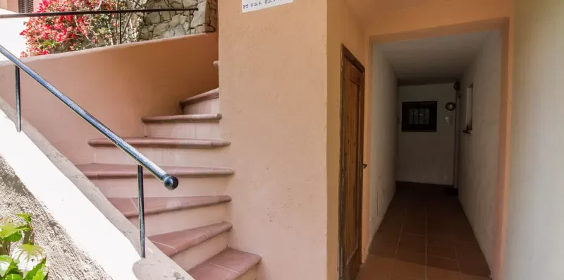An indoor stairway beside a dim hallway with a tiled floor.