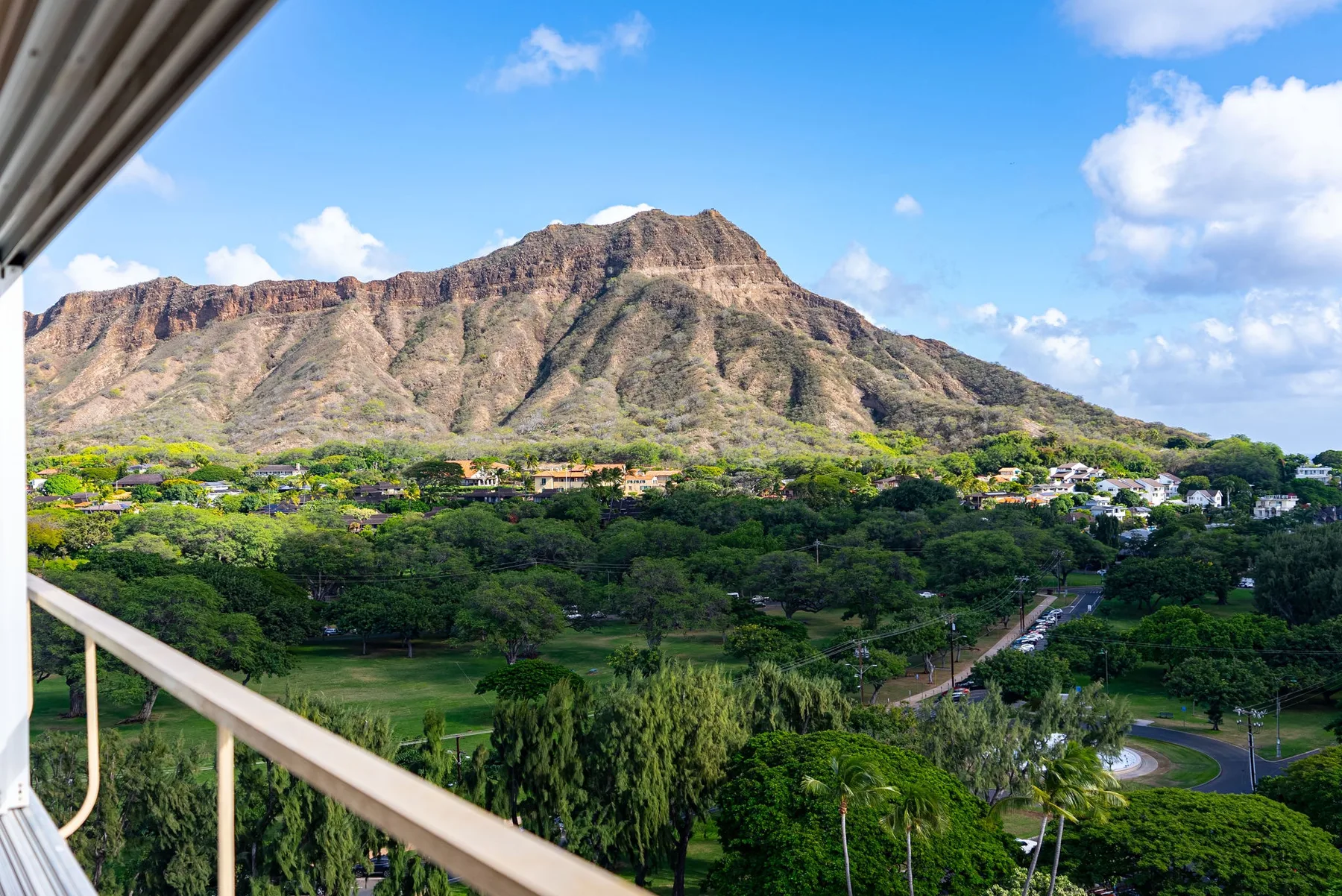 Una montaña se alza sobre un valle verde, vista desde un balcón.