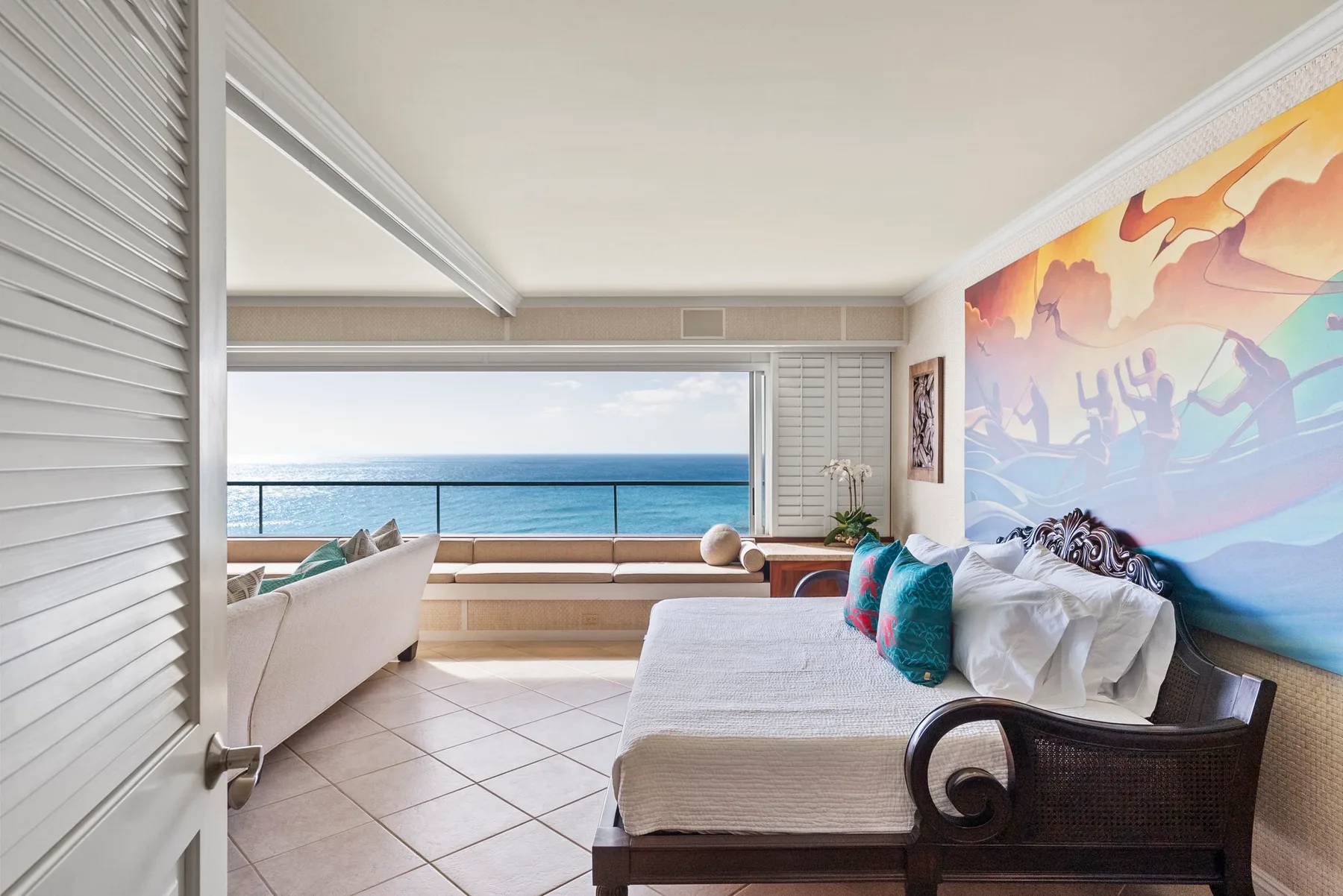 Un dormitorio luminoso da a un balcón con vistas al mar.