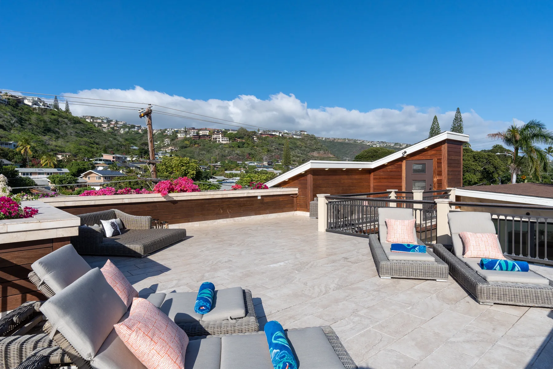 A rooftop terrace has lounge seating and views of the surrounding hillside.