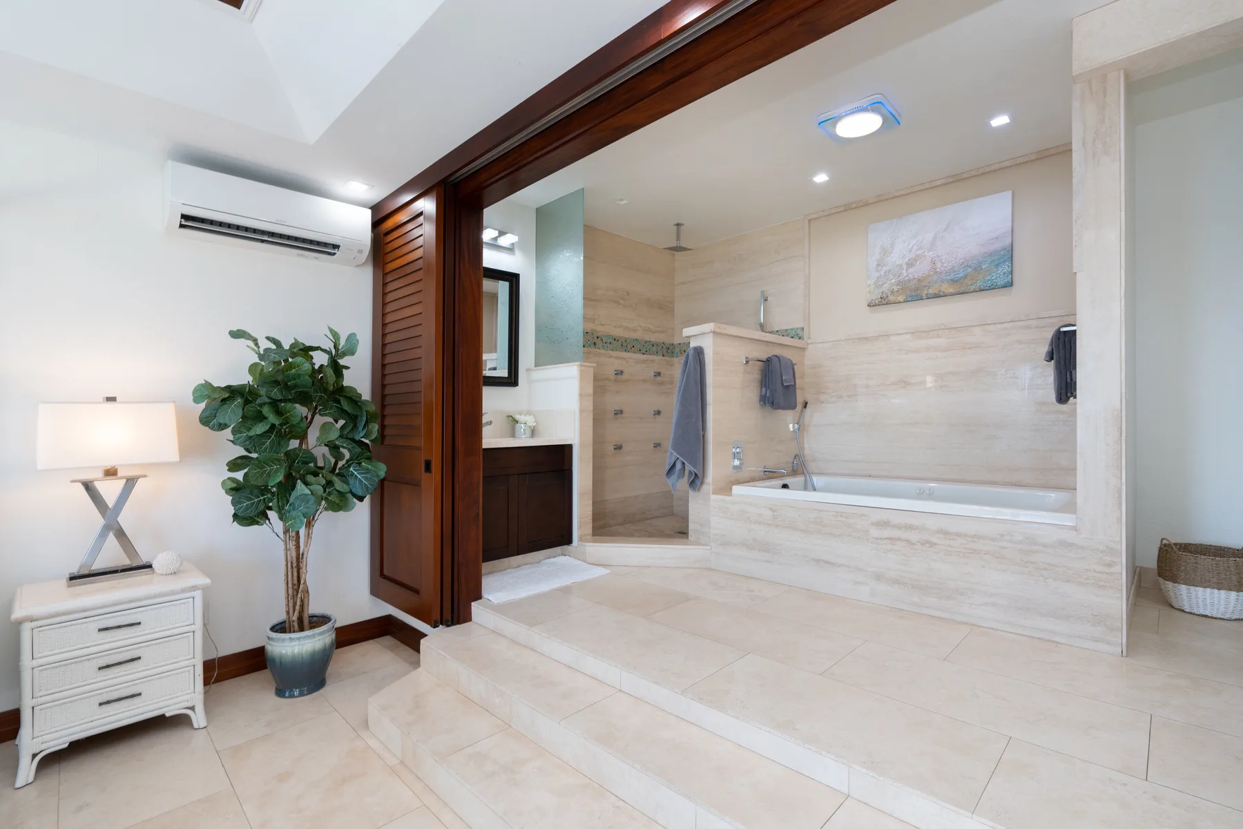 A bright bathroom with a bathtub, walk-in shower, and pale stone finishes.