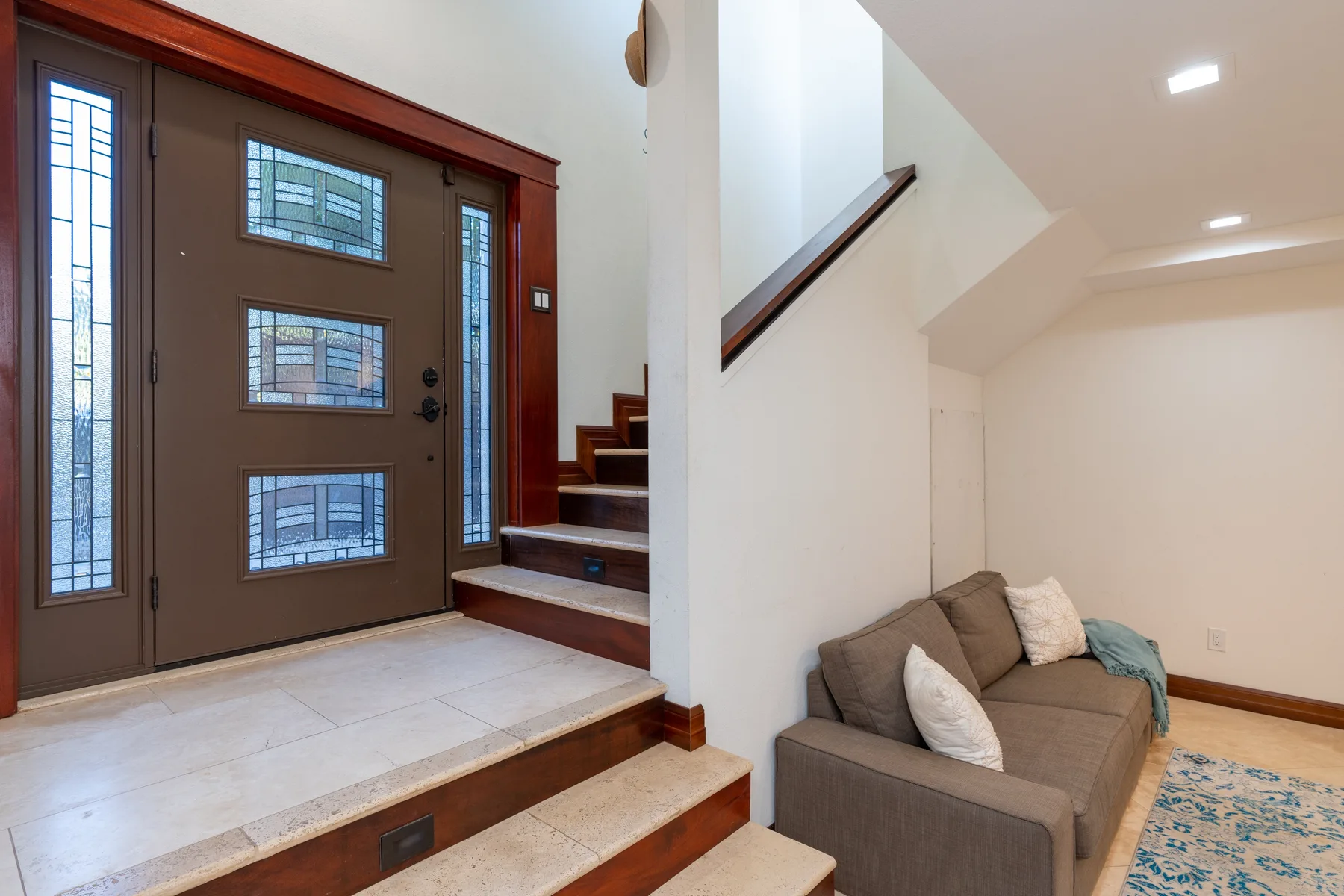 An entryway with a dark front door and a small seating area beside the stairs.