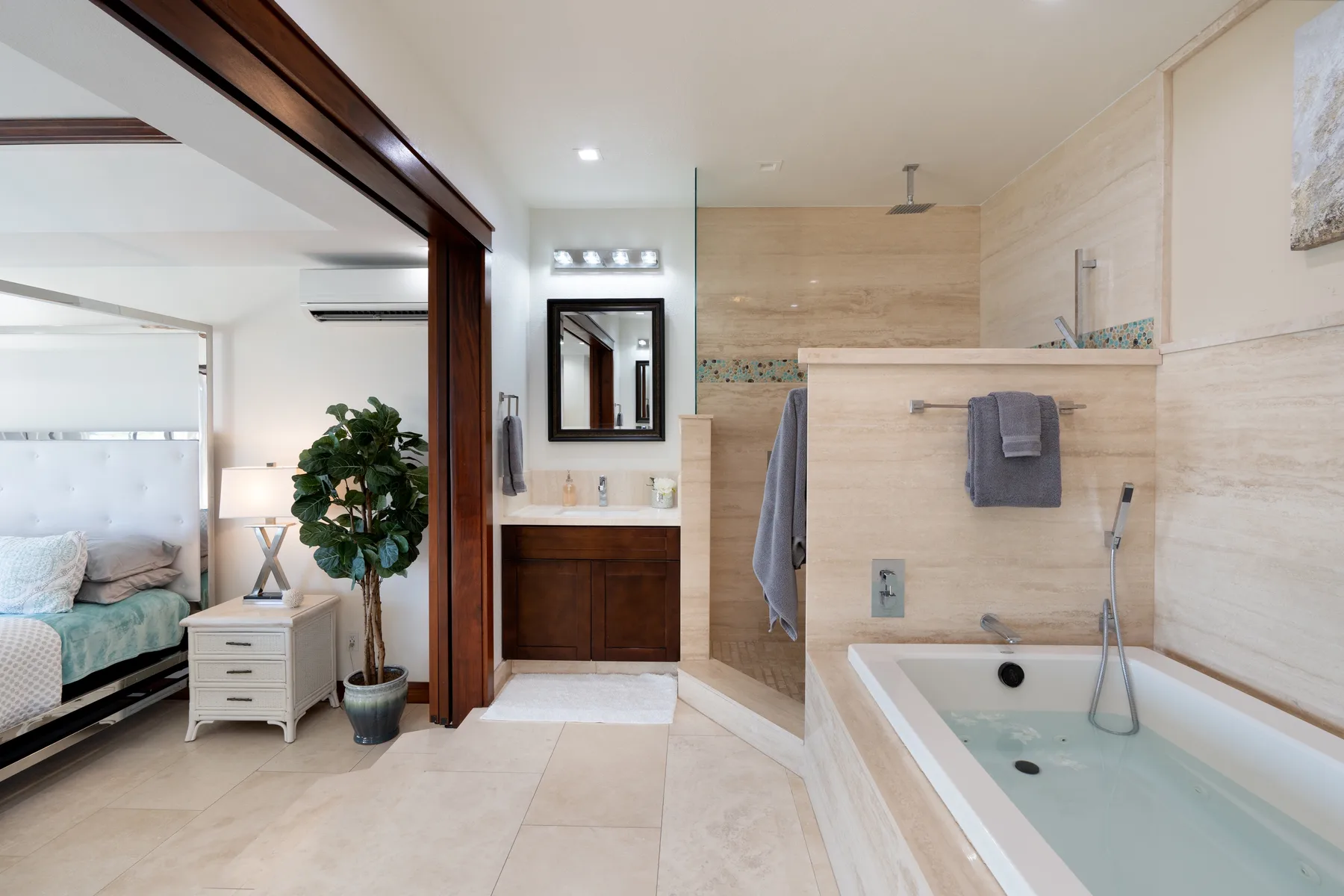 A bathroom with a bathtub, vanity, and an open view into a bedroom.