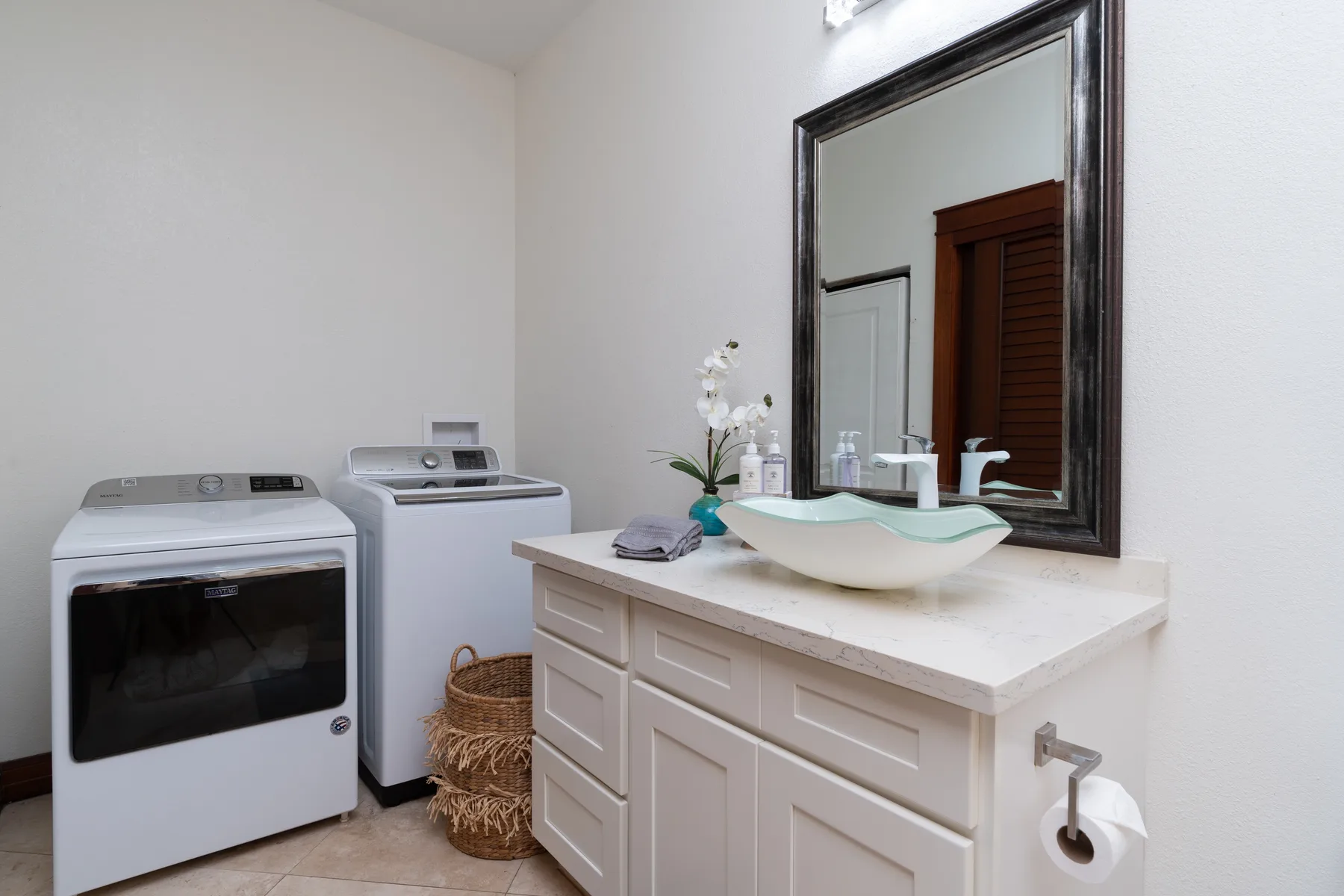 A bathroom vanity with a vessel sink and washing machines beside it.