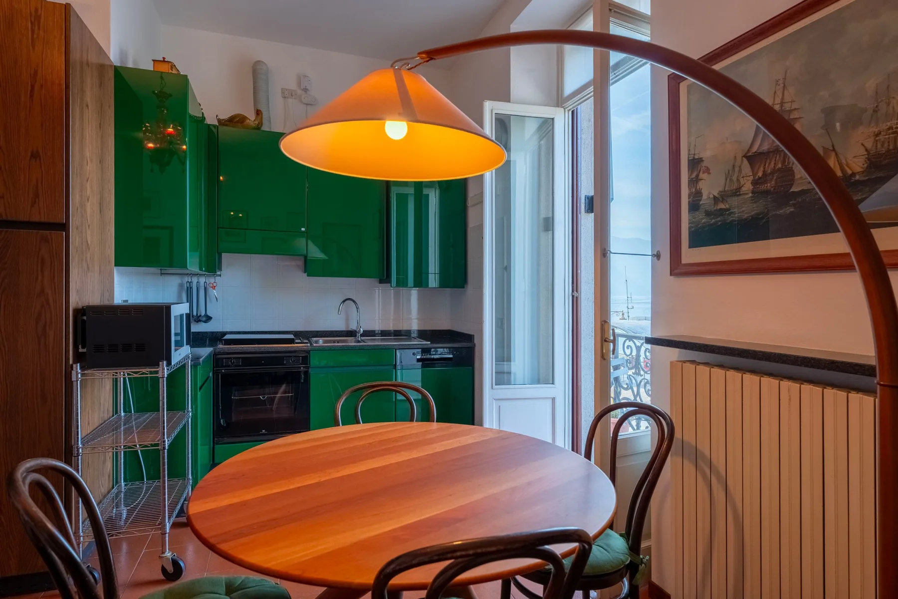 Un comedor con una mesa de madera junto a una cocina con gabinetes verdes.