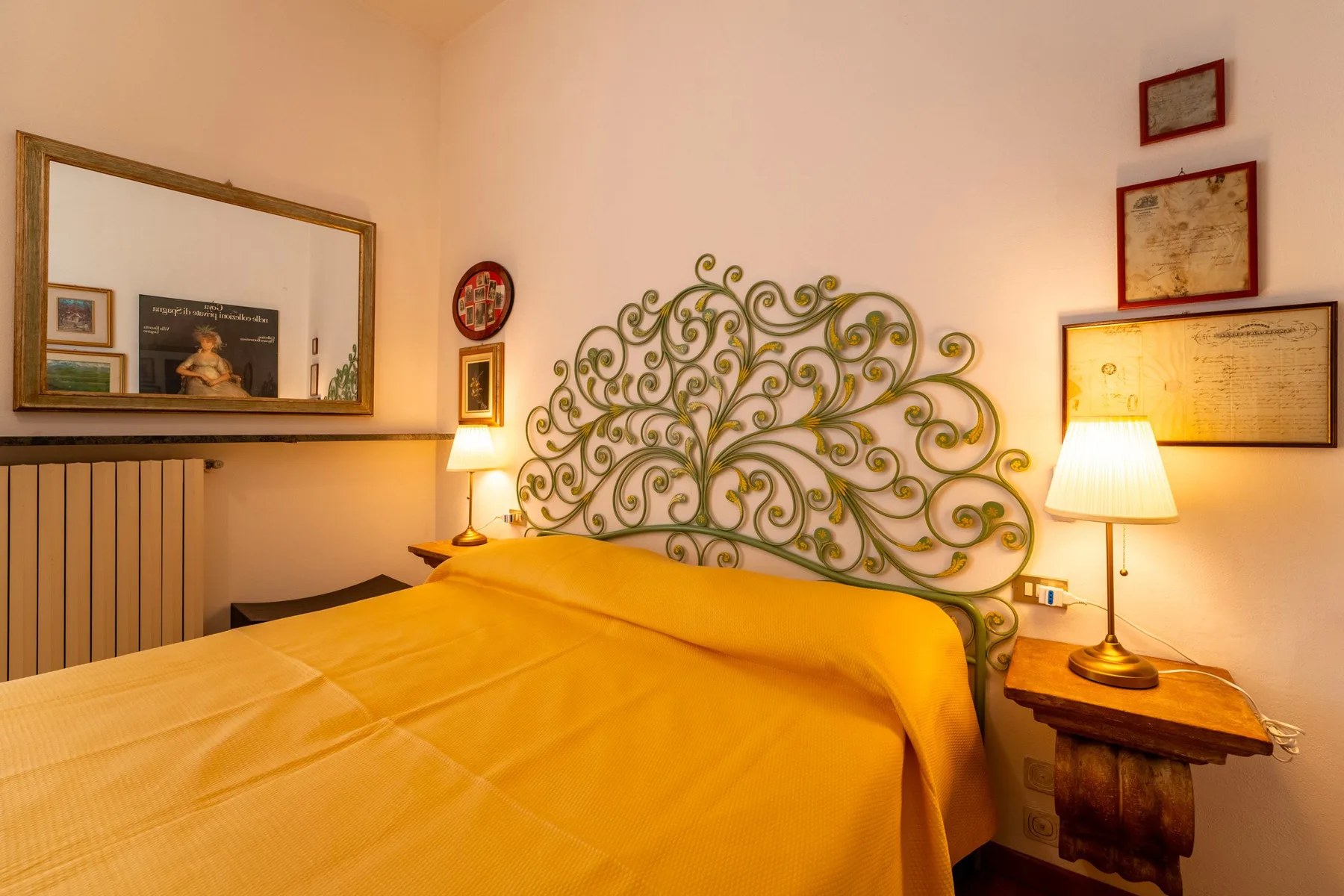 Un dormitorio con una cama, un cabecero metálico ornamentado y lámparas de noche.