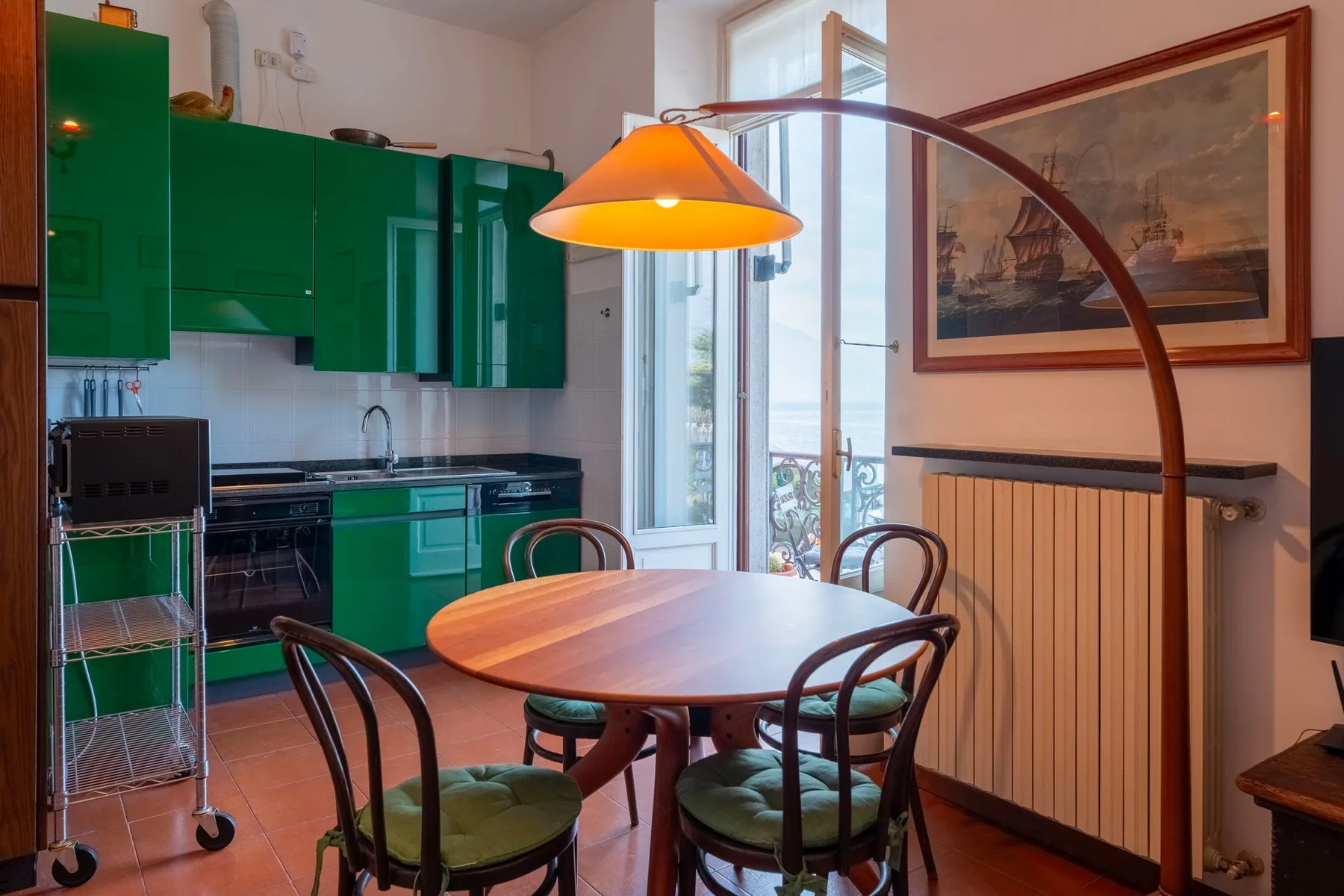 Un comedor con una mesa ovalada y gabinetes de cocina verdes.