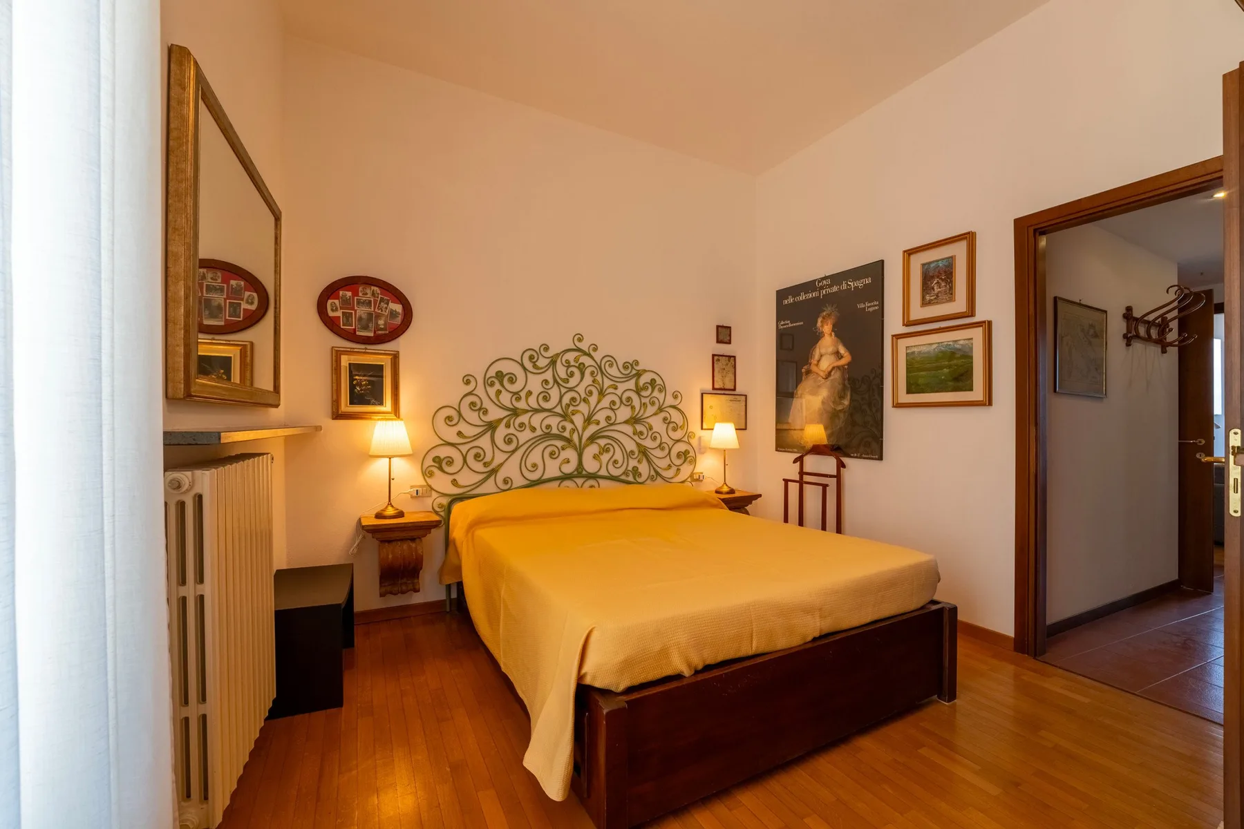Un dormitorio con una cama, un cabecero decorativo de metal y suelo de madera.