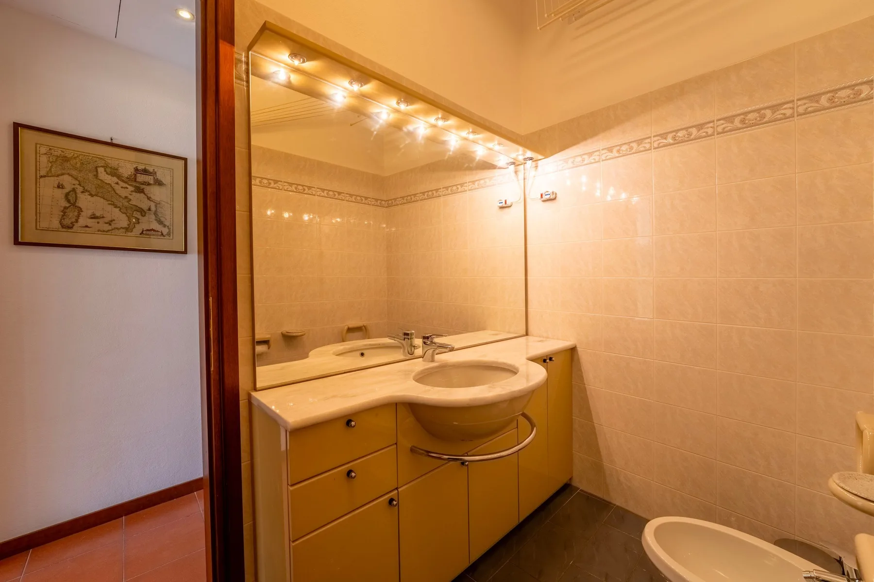 Un baño con lavabo, un espejo grande y paredes revestidas de azulejos.