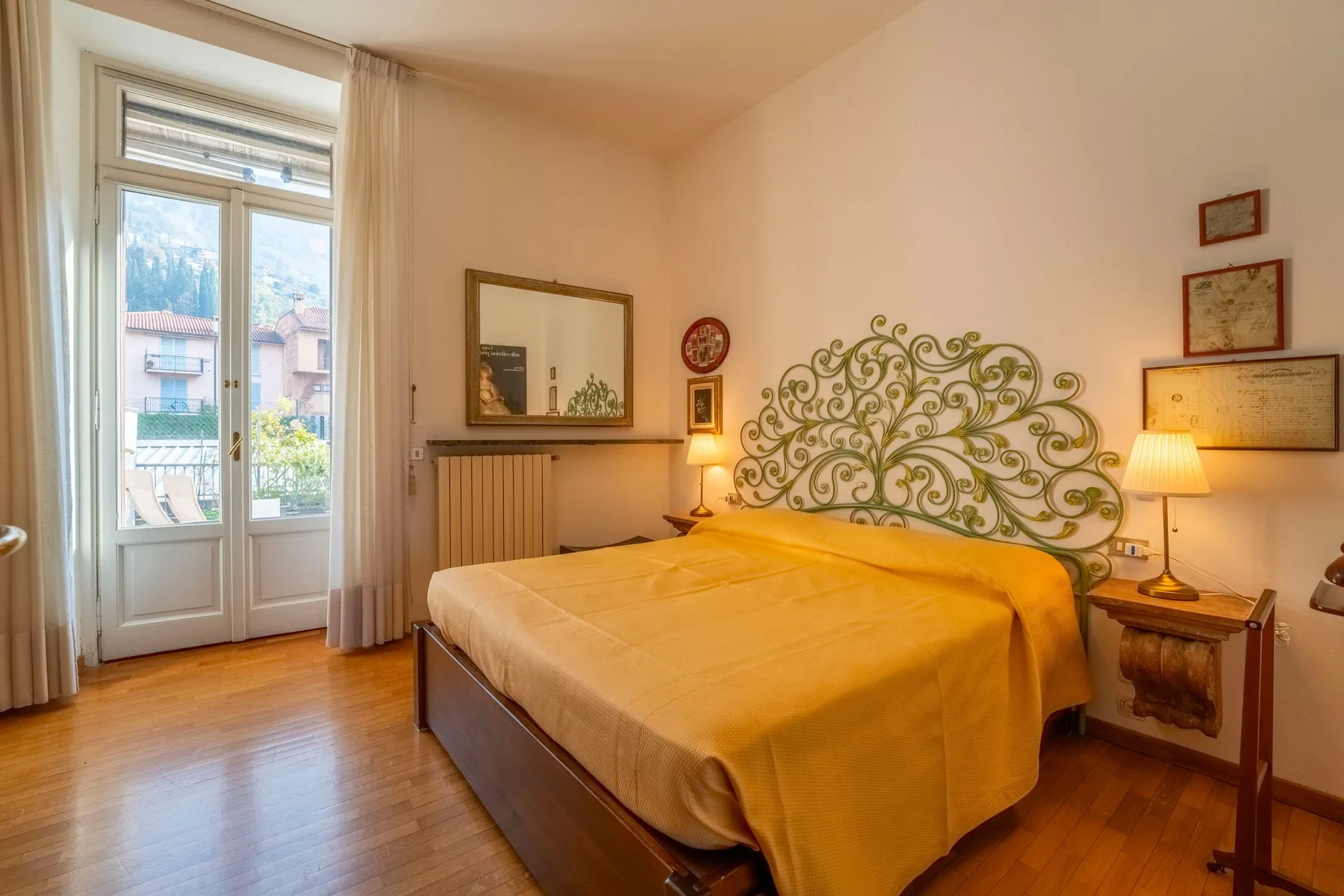 Un dormitorio con una cama grande, un cabecero decorativo de metal y puertas al balcón.