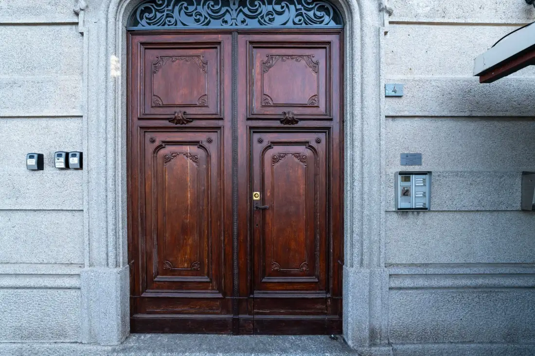 Una puerta doble de madera ornamentada en una fachada de piedra clara.