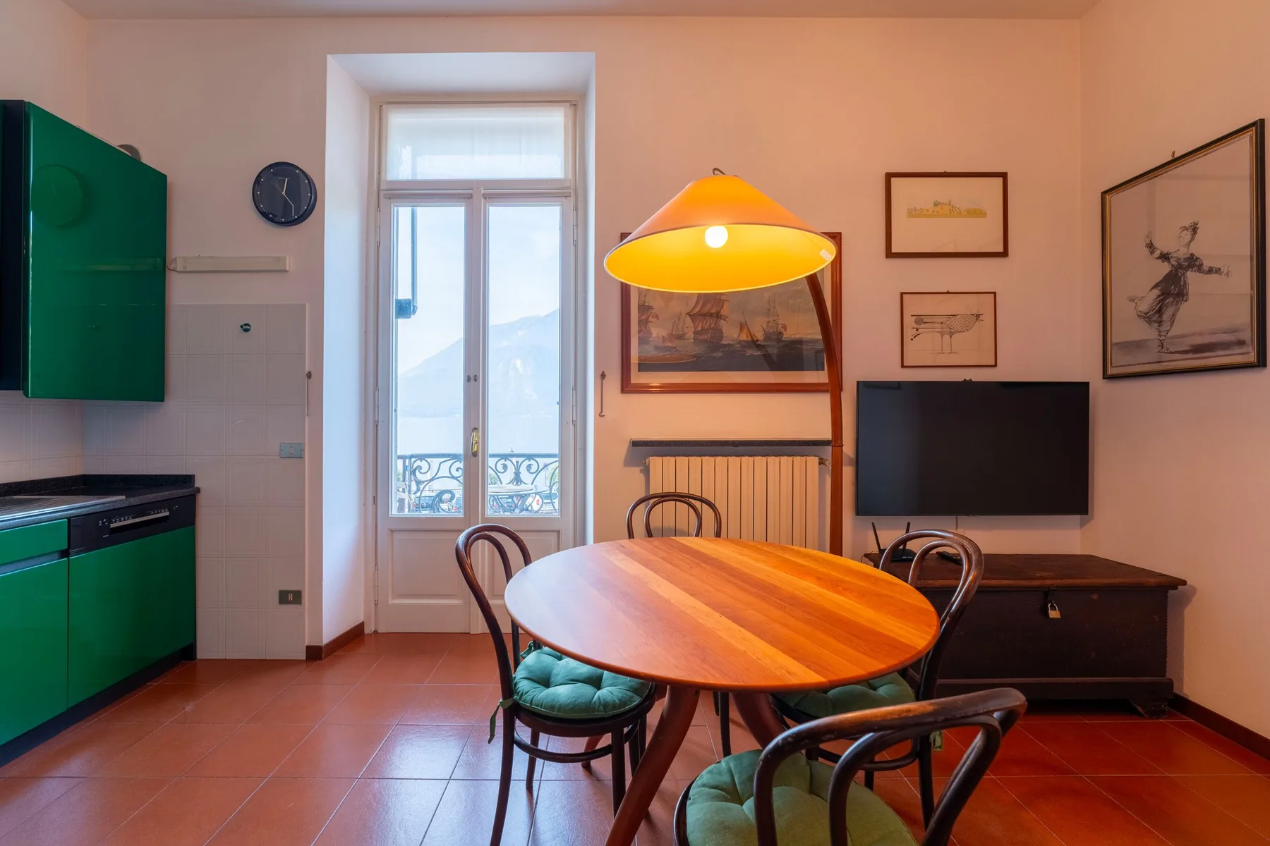 Un comedor con una mesa ovalada de madera, sillas y un televisor.