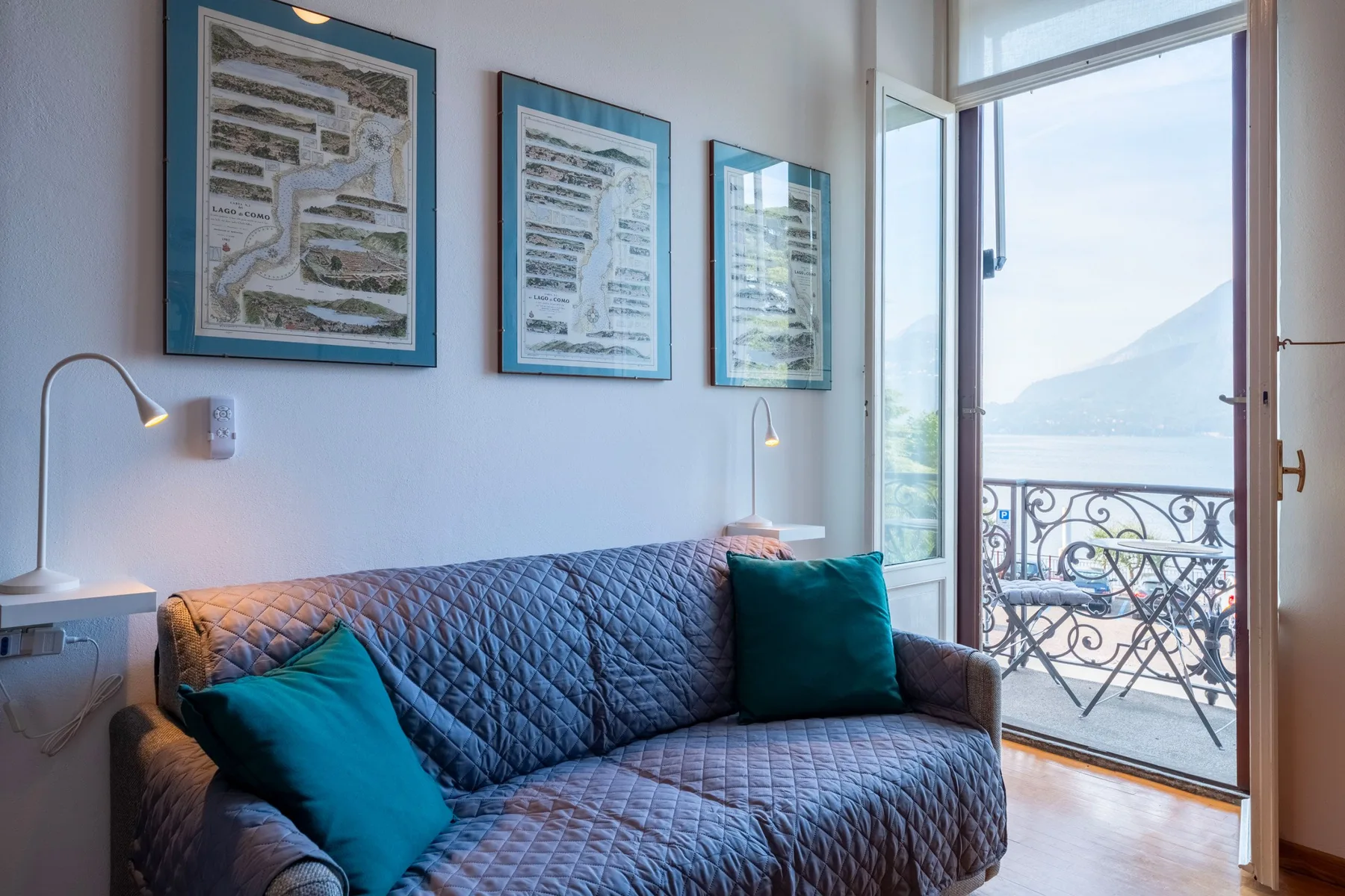 Una sala de estar con un sofá estampado junto a una puerta abierta al balcón.