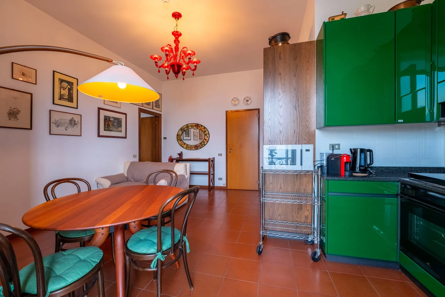Comedor junto a una cocina, con una mesa de madera y armarios verdes.