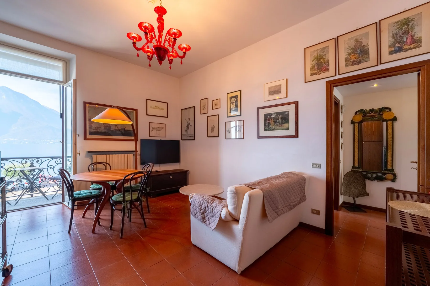 Una sala de estar con asientos, una mesa de comedor y una puerta de vidrio que da a un balcón.