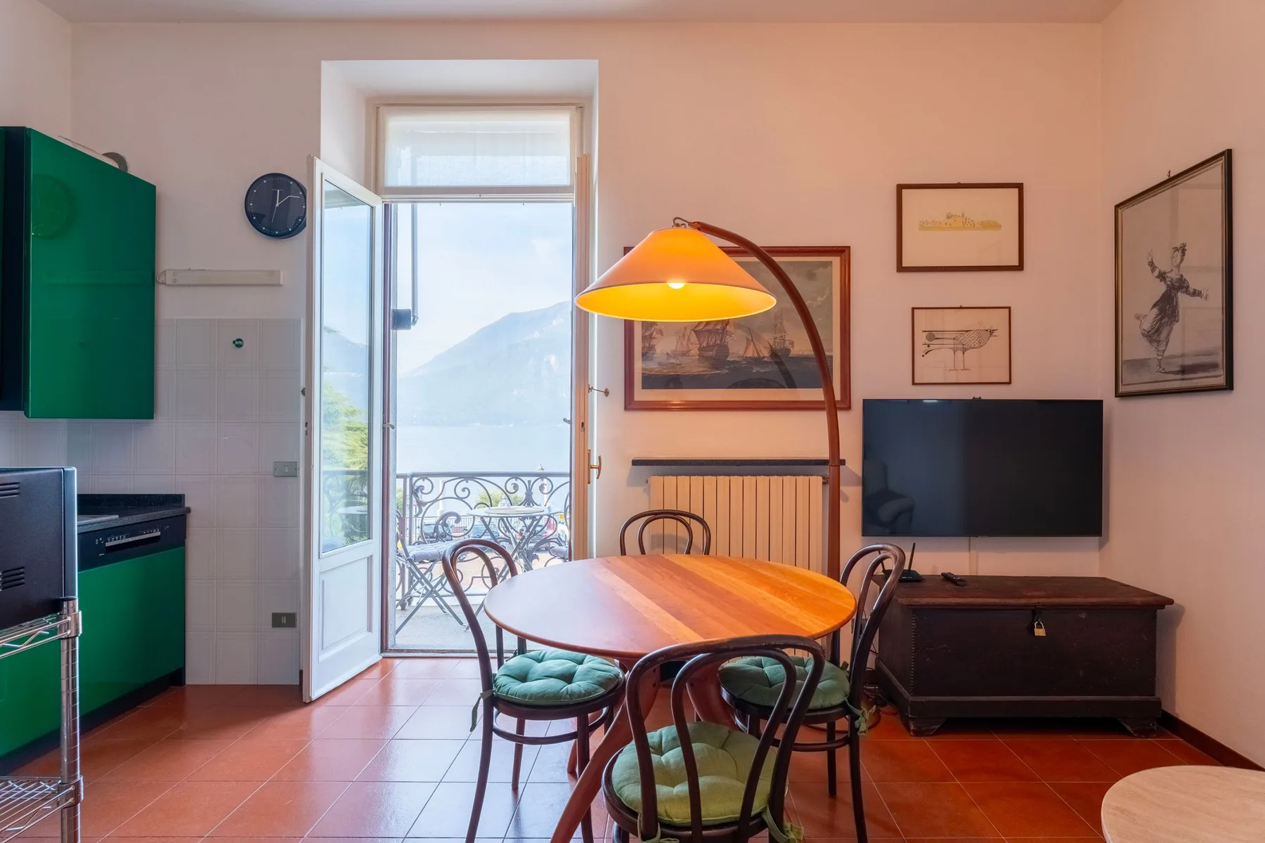 Un comedor con una mesa de madera, una lámpara colgante y un televisor.