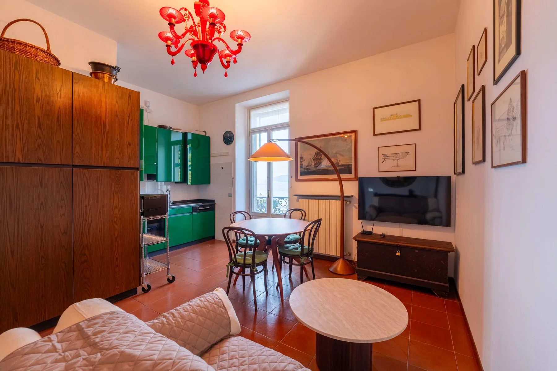 Una sala de estar y comedor con televisor, mesa de comedor y lámpara roja.