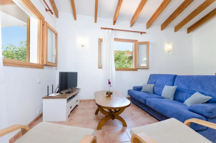 Una sala luminosa con asientos azules, una mesa de centro y vigas expuestas en el techo.