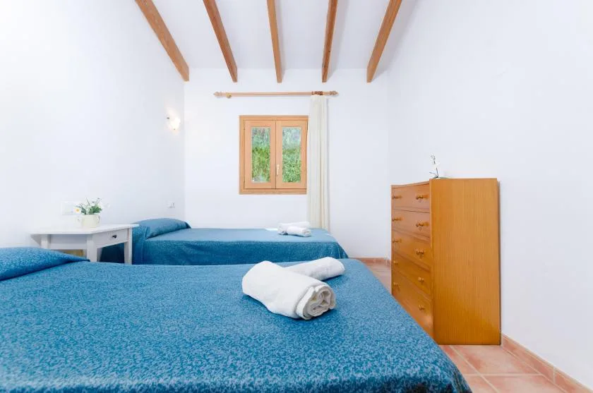 Un dormitorio con dos camas cubiertas con colchas azules y una cómoda de madera.