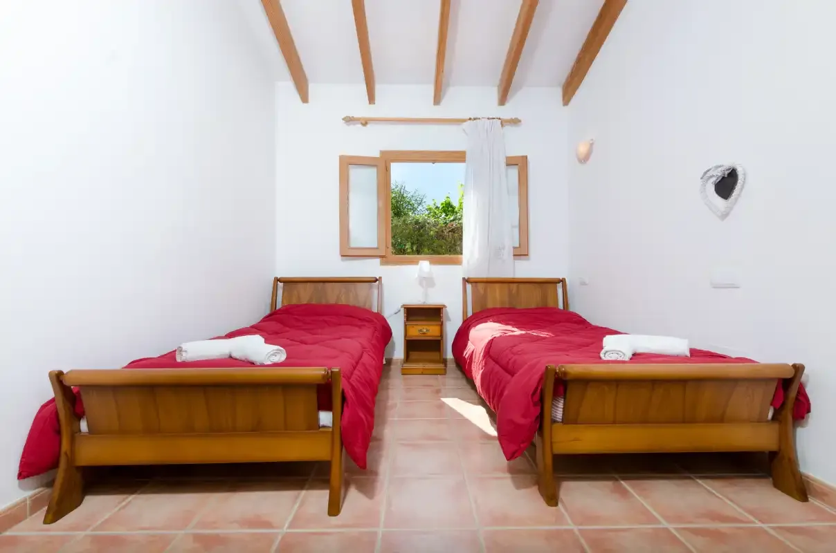 Un dormitorio luminoso con dos camas individuales y una ventana entre ellas.